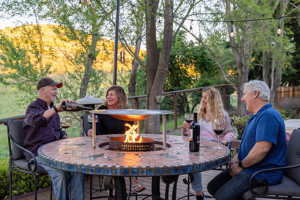 Group of people enjoying around a fire pit equipped with HeatSaver heat deflector