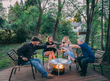 Load image into Gallery viewer, People sitting around a fire pit that uses HeatSaver heat deflector and cover
