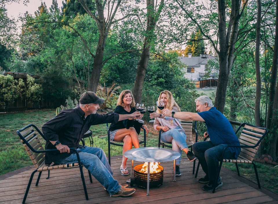 People sitting around a fire pit that uses HeatSaver heat deflector and cover