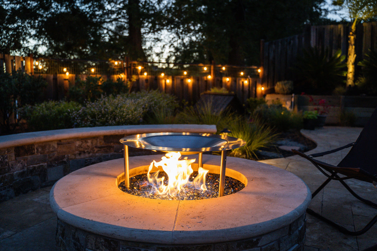 HeatSaver fire pit heat deflector and cover in a backyard setting with lights