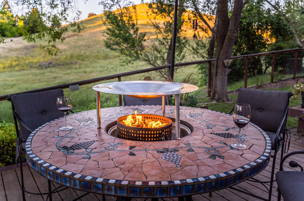 HeatSaver fire pit heat deflector on a patio table, wine glasses nearby
